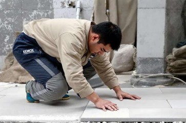 Worker applying tile adhesive in Nigeria on floor tiles during installation